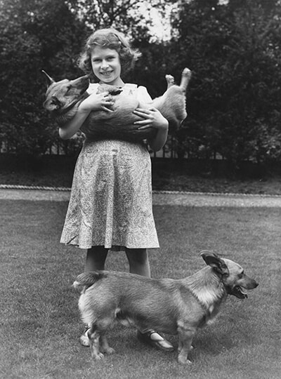 230123_Princess-Elizabeth-(later-Queen-Elizabeth-II)-with-two-corgi-dogs-at-her-home-at-145-Piccadilly,-London,-July-1936.jpg