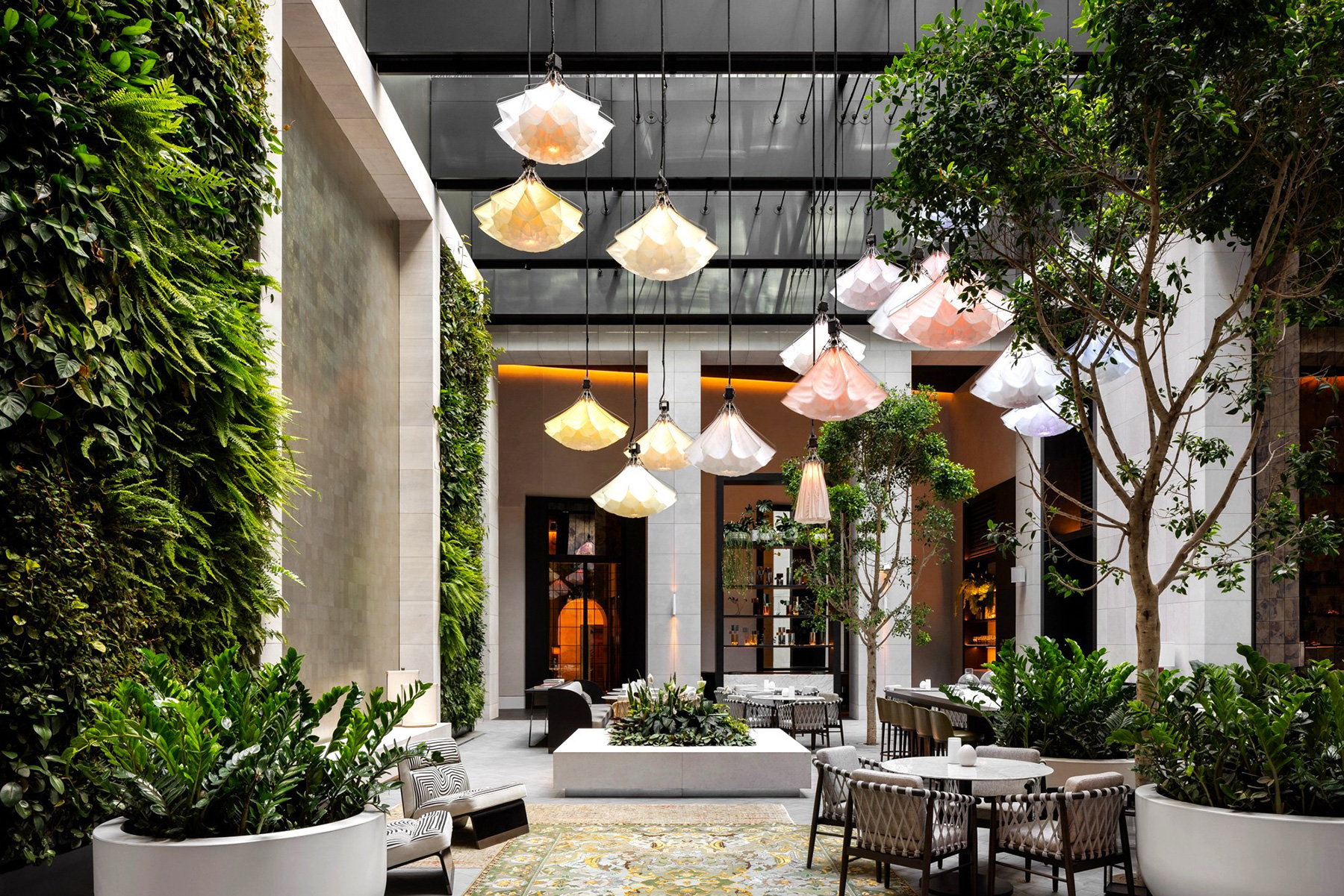 Interior courtyard with lush vertical gardens, modern seating, and pendant lamps hanging from the ceiling.