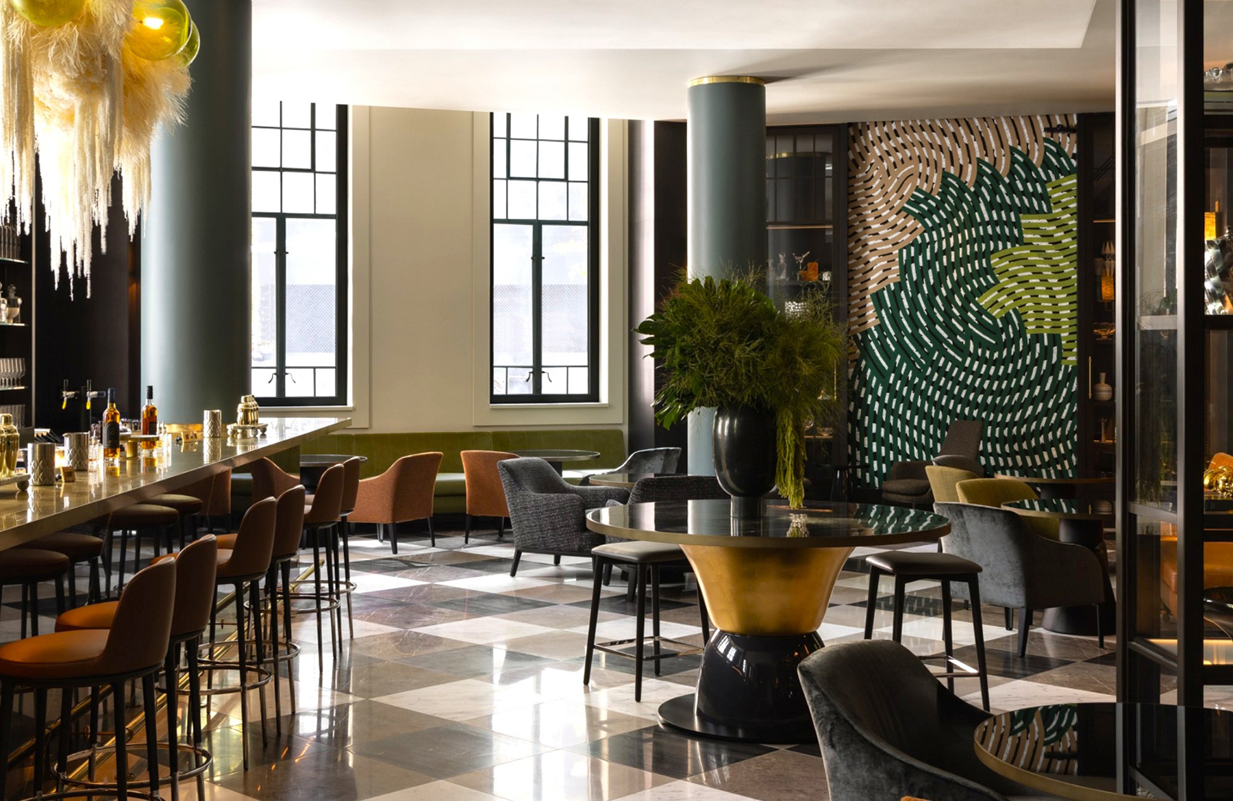 Luxurious bar lounge with a long marble counter, brown bar stools, tall windows, and a large green plant centerpiece.