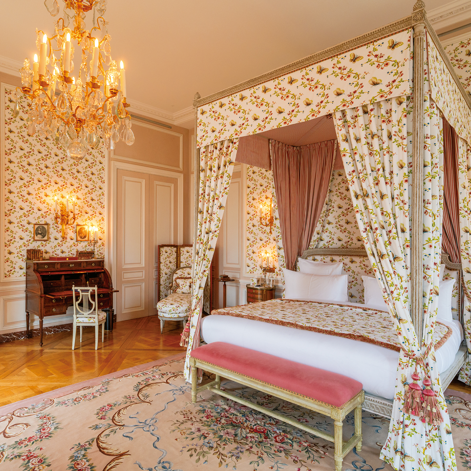 Luxurious vintage bedroom with a floral four-poster bed, chandelier, and patterned wallpaper in warm tones.