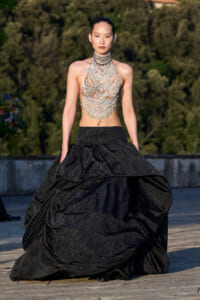 Model wearing a sparkling multi-layer silver necklace bodice with a dramatic black ball gown outdoors.