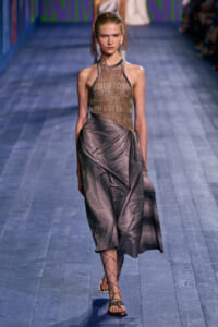 Model walks the runway in a metallic mesh halter top and a draped satin skirt with strappy sandals.