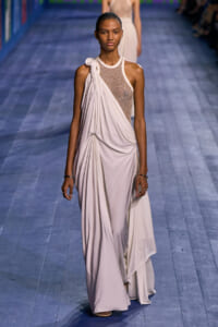 Model walks the runway in a cream draped gown with a beaded mesh bodice and one-shoulder detail.