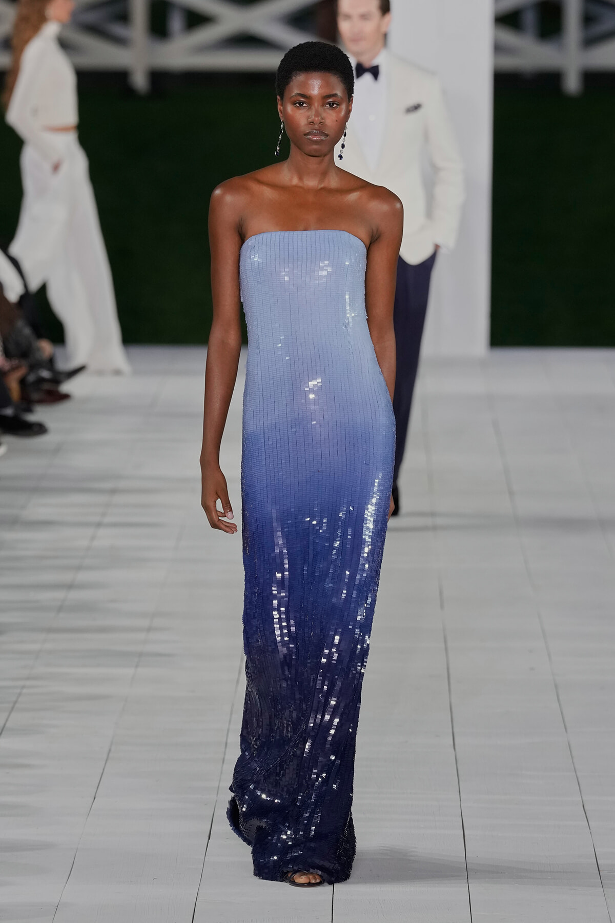 Female model walks the runway in a strapless gradient blue sequined gown, fading from light blue at the bodice to deep navy at the hem.