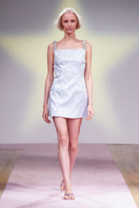 Model walks the runway in a pale blue floral mini dress with beaded straps and silver sandals.
