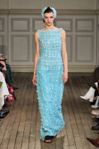 Runway model in a light blue, sleeveless gown covered with 3D floral appliqués and a matching headband.