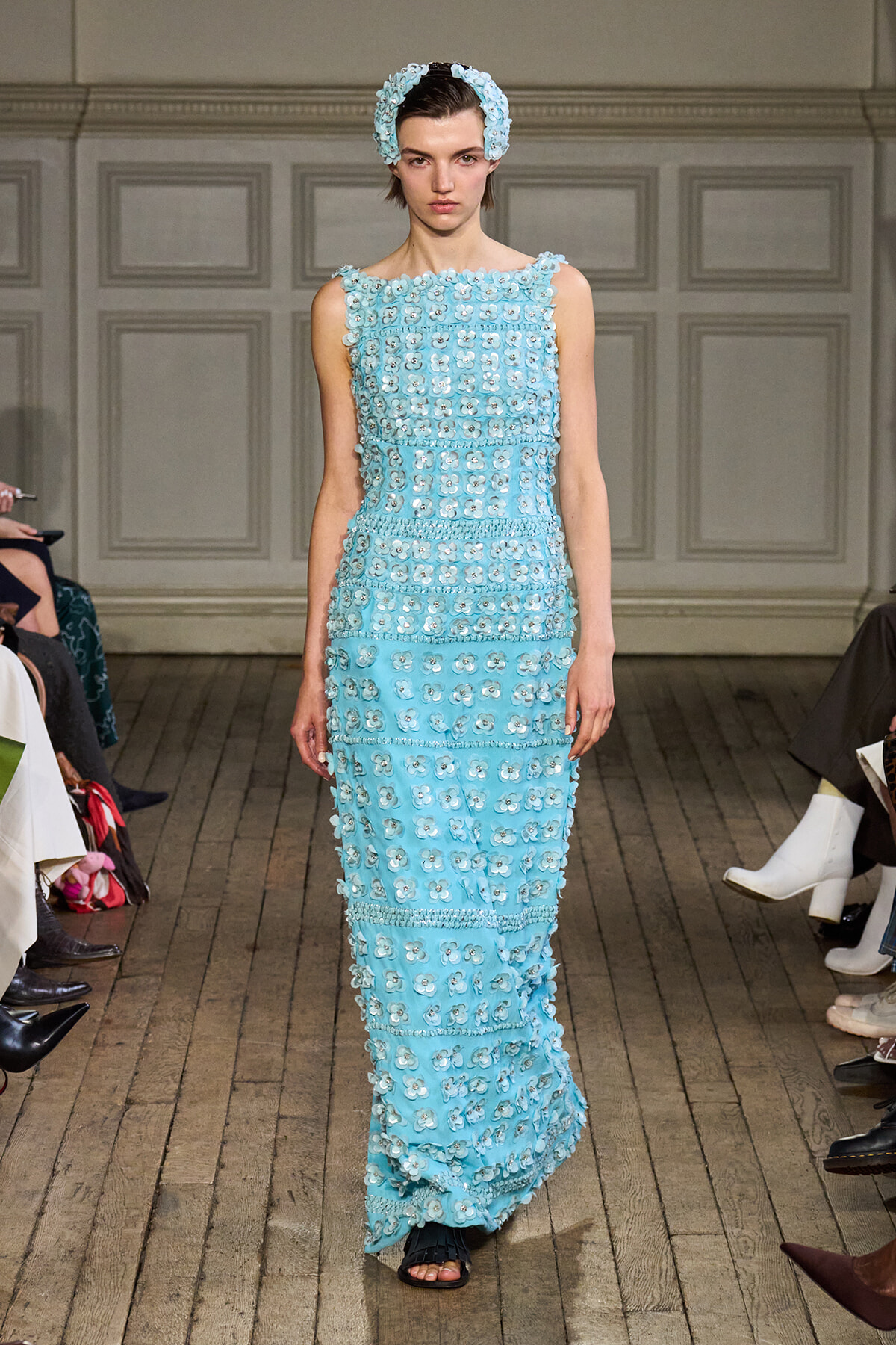 Runway model in a light blue, sleeveless gown covered with 3D floral appliqués and a matching headband.
