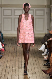 Model walking the runway in a pink crochet mini dress with floral appliqués and a matching headband.