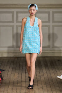Model on a runway wearing a turquoise mini dress with 3D floral appliqués and matching headband.