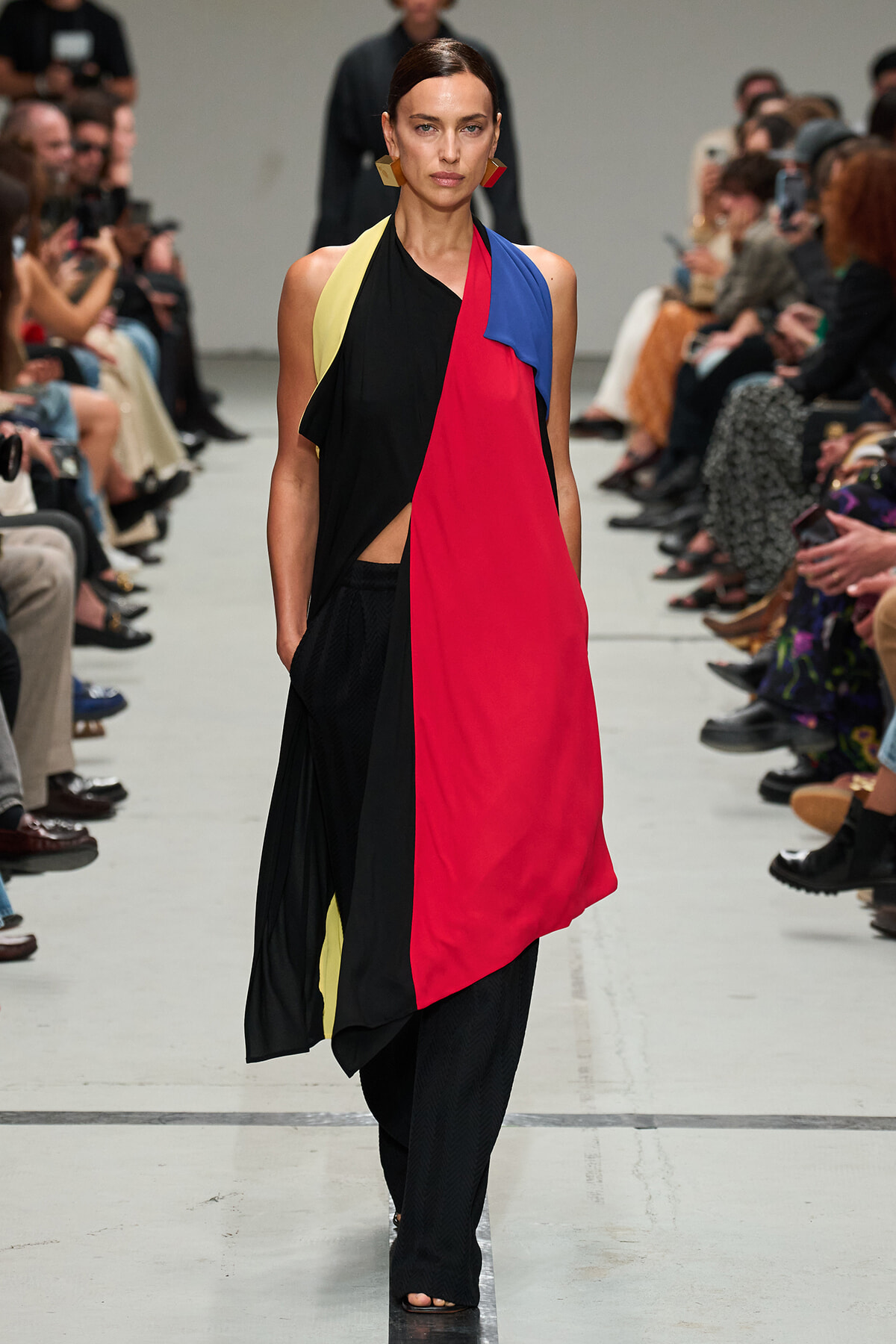 Model walks a runway wearing a color-blocked sleeveless dress with red, black, yellow, and blue panels.