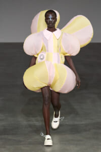 Model walking runway in a pastel pink and yellow balloon dress with oversized puff sleeves and rounded skirt shapes.