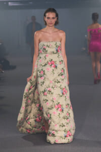 Model walks the runway in a strapless beige floral gown with a quilted, voluminous skirt.