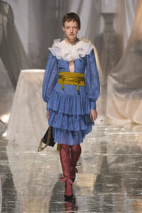 Runway look: blue polka-dot tiered dress with a white frilly collar, yellow waist sash, and burgundy lace tights.