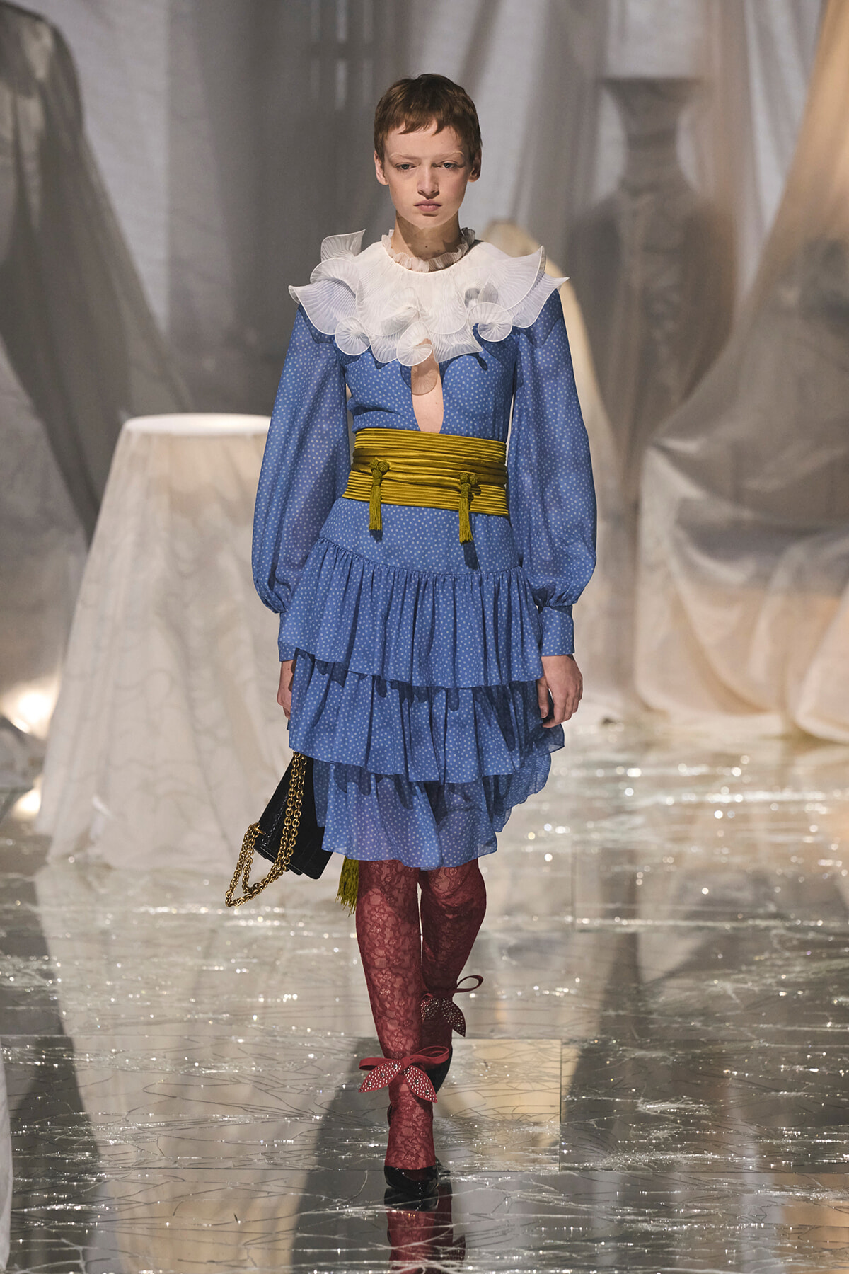 Runway look: blue polka-dot tiered dress with a white frilly collar, yellow waist sash, and burgundy lace tights.