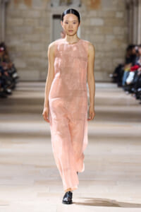 Model walking a pale pink sleeveless jumpsuit down a fashion-show runway.