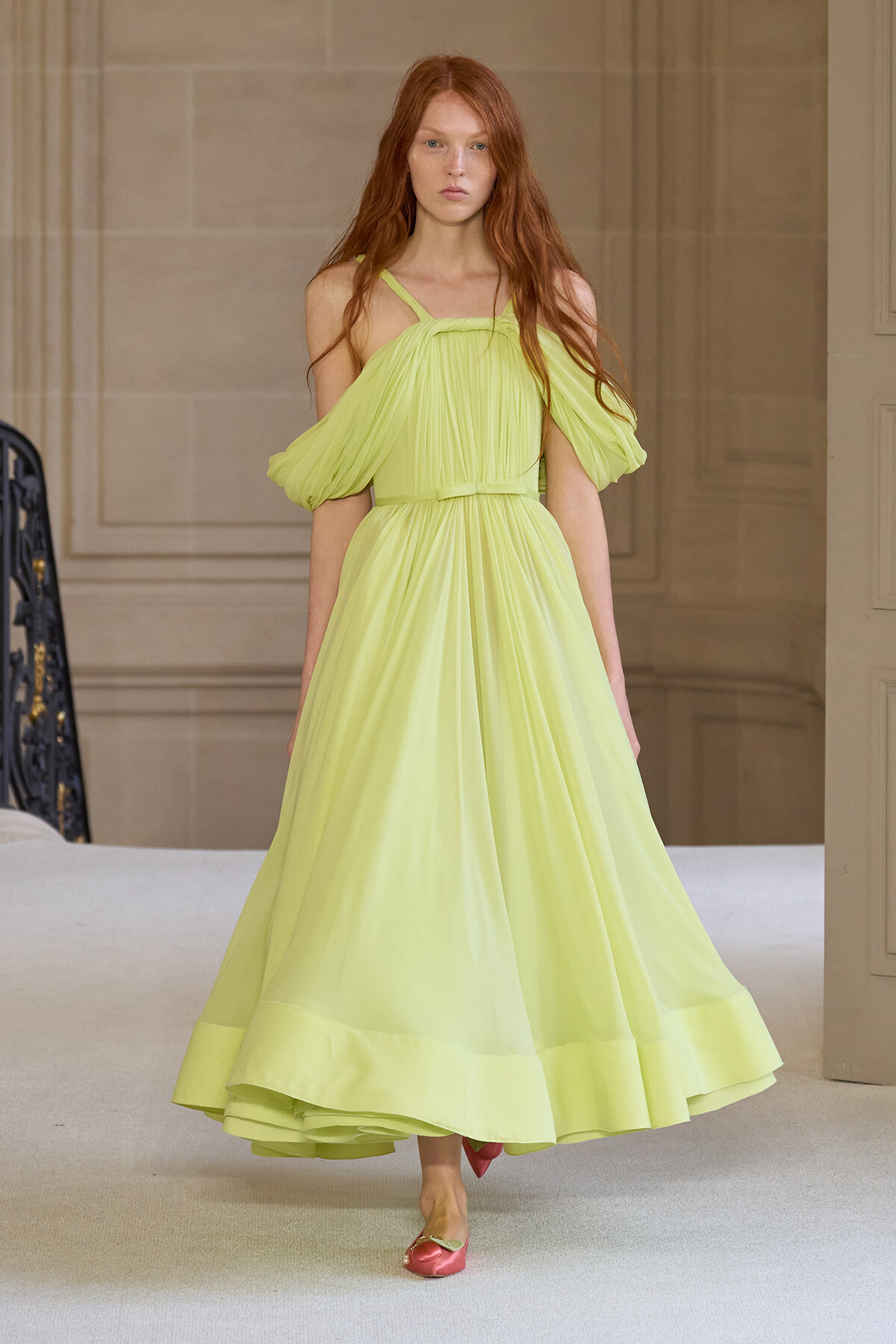 Model walks the runway in a lime-green off-shoulder chiffon gown with a cinched waist and voluminous pleated skirt.