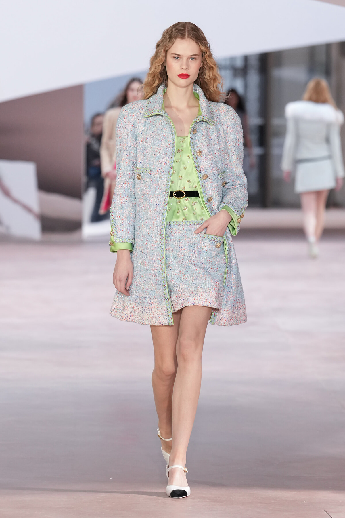 Model walks the runway in a pastel speckled tweed coat with lime-green blouse and belt