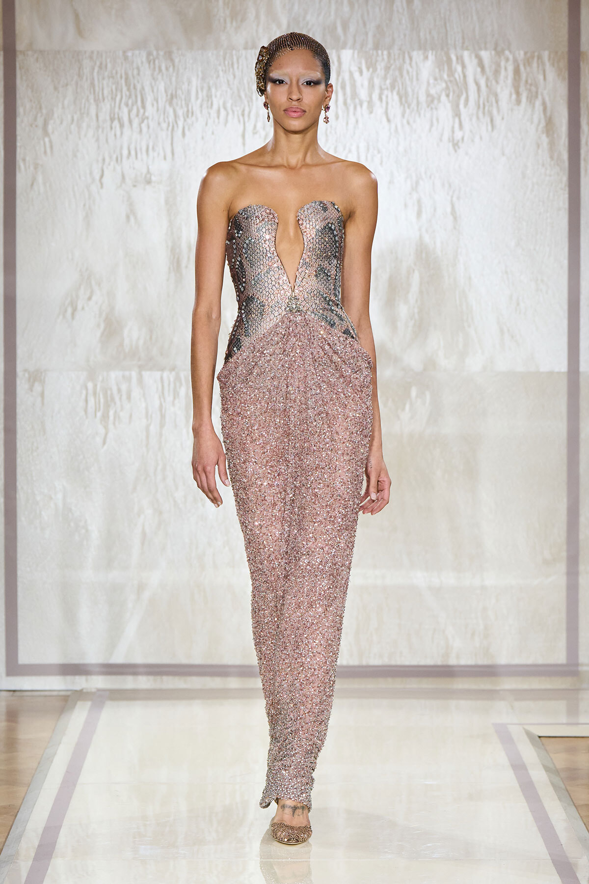 Model walks the runway in a strapless pink sequin gown with a plunging neckline.