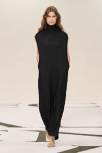 Model walking the runway in a sleeveless black turtleneck jumpsuit with wide legs.