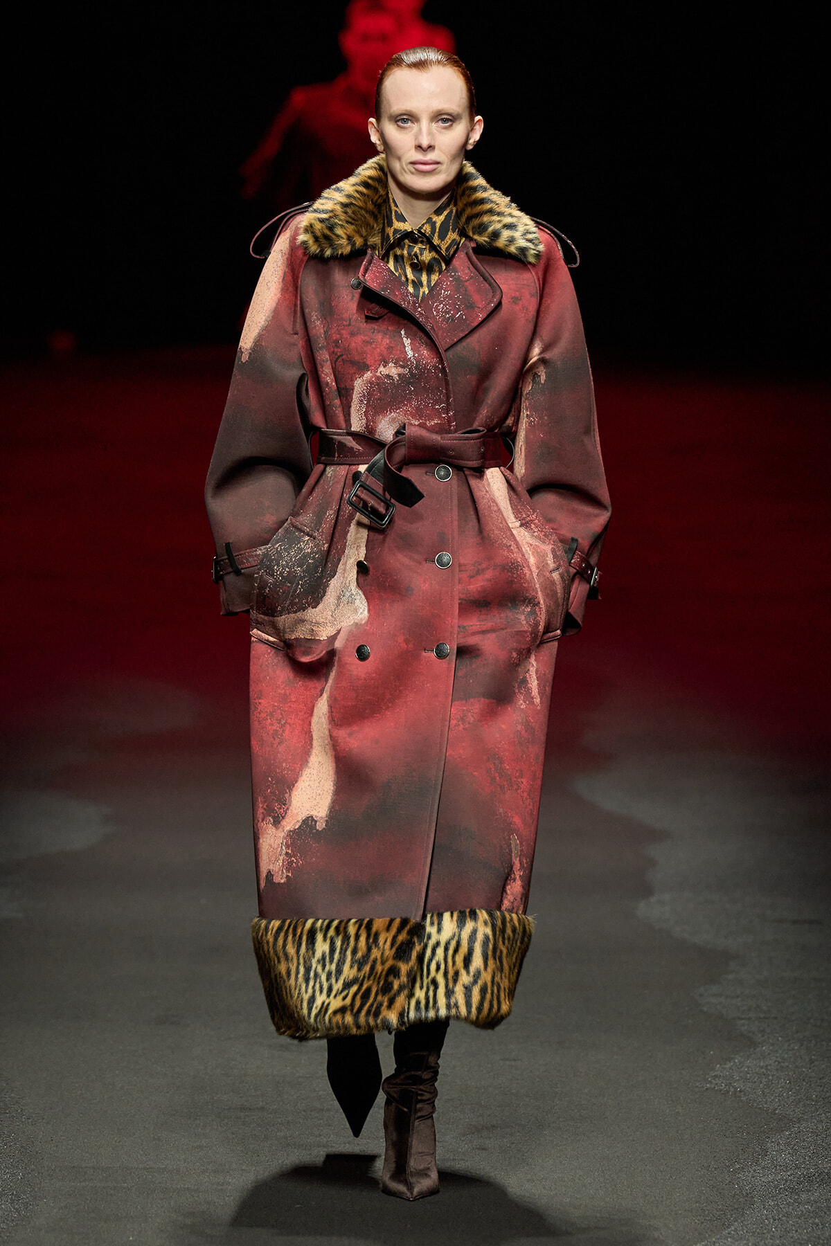 Runway model in a long burgundy coat with leopard fur trim at collar and cuffs, belted at the waist.