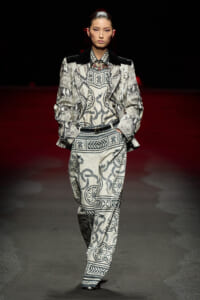Model walks a fashion runway in a monochrome snakeskin-pattern suit with an oversized jacket and matching trousers.