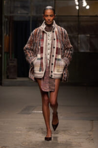 Model walks the runway in a chunky multicolor plaid coat with large pockets and buttons.