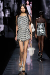 Model walking the runway in a silver beaded fringe mini dress with strappy heels.