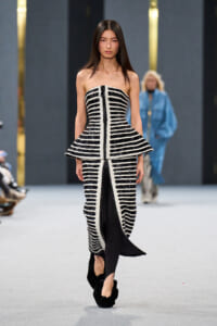 Strapless black-and-white striped gown with a structured peplum on a runway model.