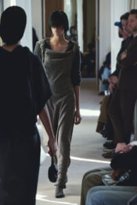 Model in metallic gold jumpsuit walking the fashion show runway.