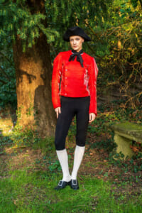 Person in a red pirate-style jacket and black tricorn hat standing in a garden setting.