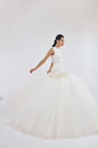 Side view of a model wearing a white lace wedding dress with a dramatic, full tulle skirt.
