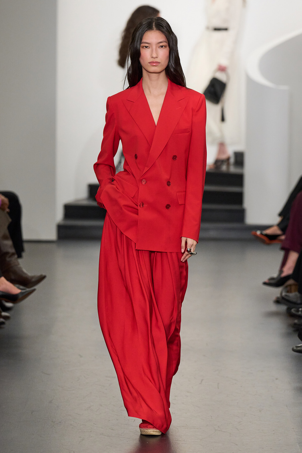 Model walks the runway in a bright red double-breasted suit with matching wide-leg trousers.