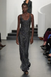 Model walks the runway in a long, sparkling metallic bead gown with a scoop neckline and black sandals.