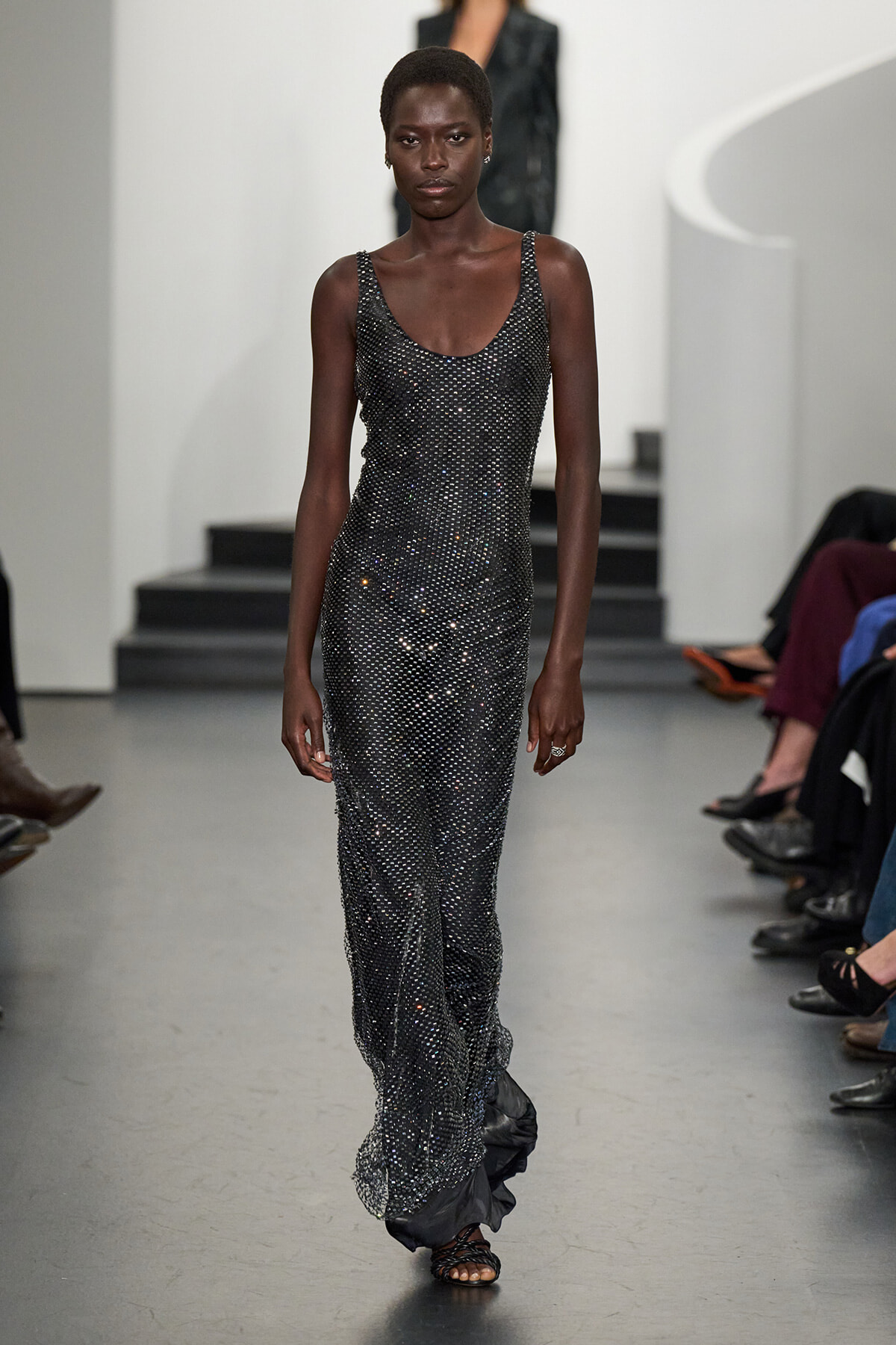 Model walks the runway in a long, sparkling metallic bead gown with a scoop neckline and black sandals.