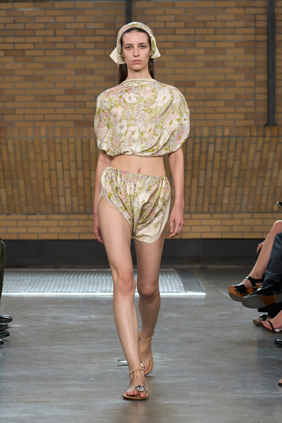 Model walks the runway in a beige floral two-piece set with a matching headscarf.
