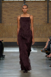 Model walking the runway in a burgundy fringe gown with spaghetti straps.