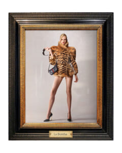 Fashion photo of a model in a tiger-print fur coat, black heels, and a small crossbody bag, holding sunglasses, inside an ornate frame labeled La Bomba.