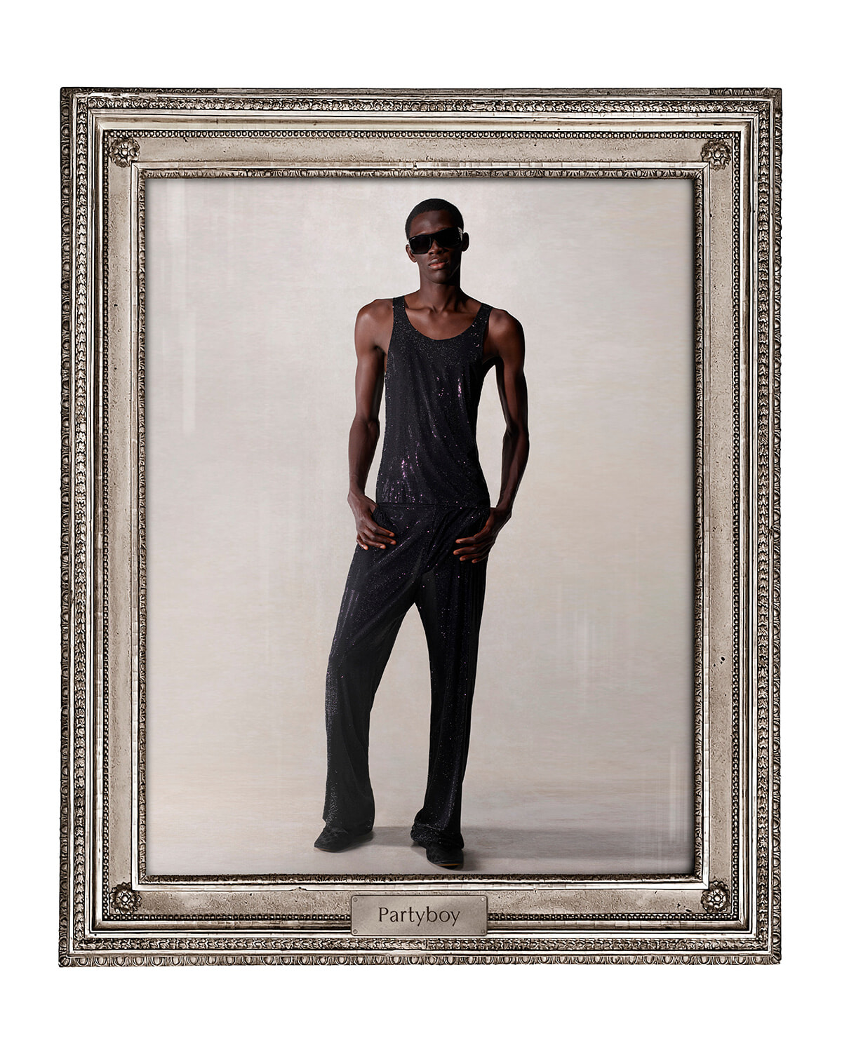Framed portrait of a tall man in a black sequin tank top and trousers, wearing sunglasses, posing confidently.
