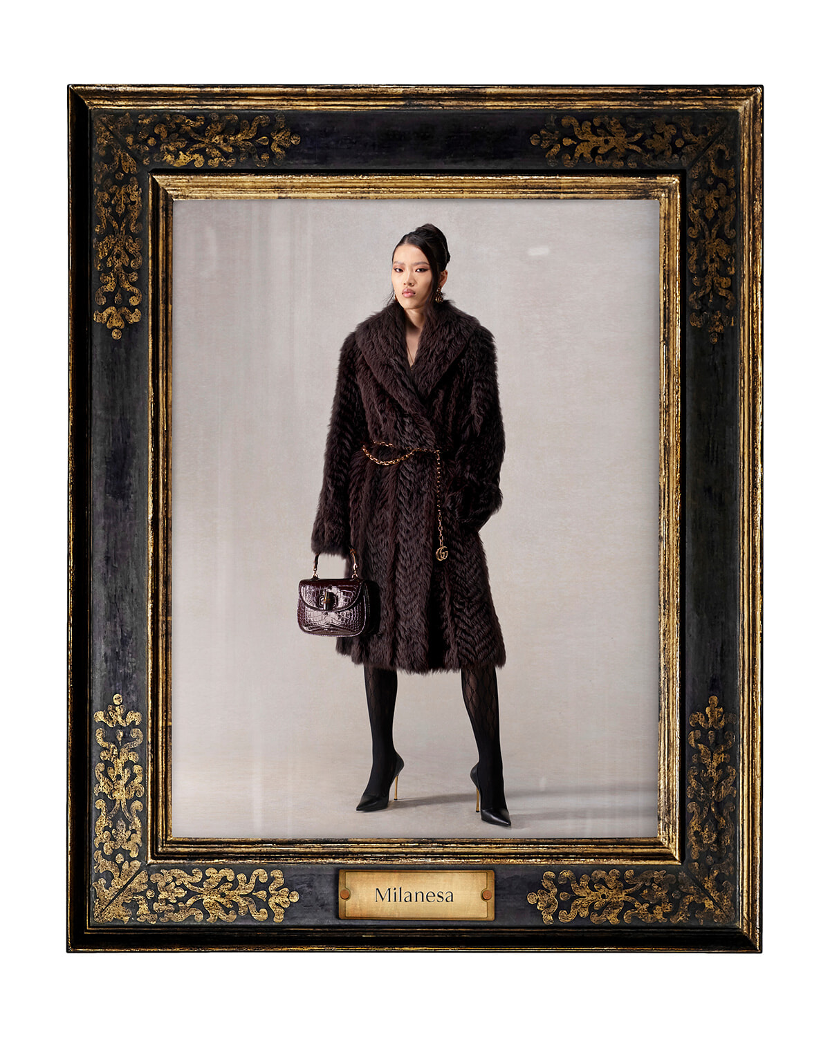Fashion photo of a woman in a dark fur coat with a gold chain belt and handbag, standing against a neutral backdrop inside an ornate framed portrait frame labeled Milanesa.