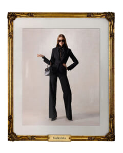 Model in a black pantsuit with sunglasses posing with a black handbag inside a gilded gallery frame labeled 'Gallerista'