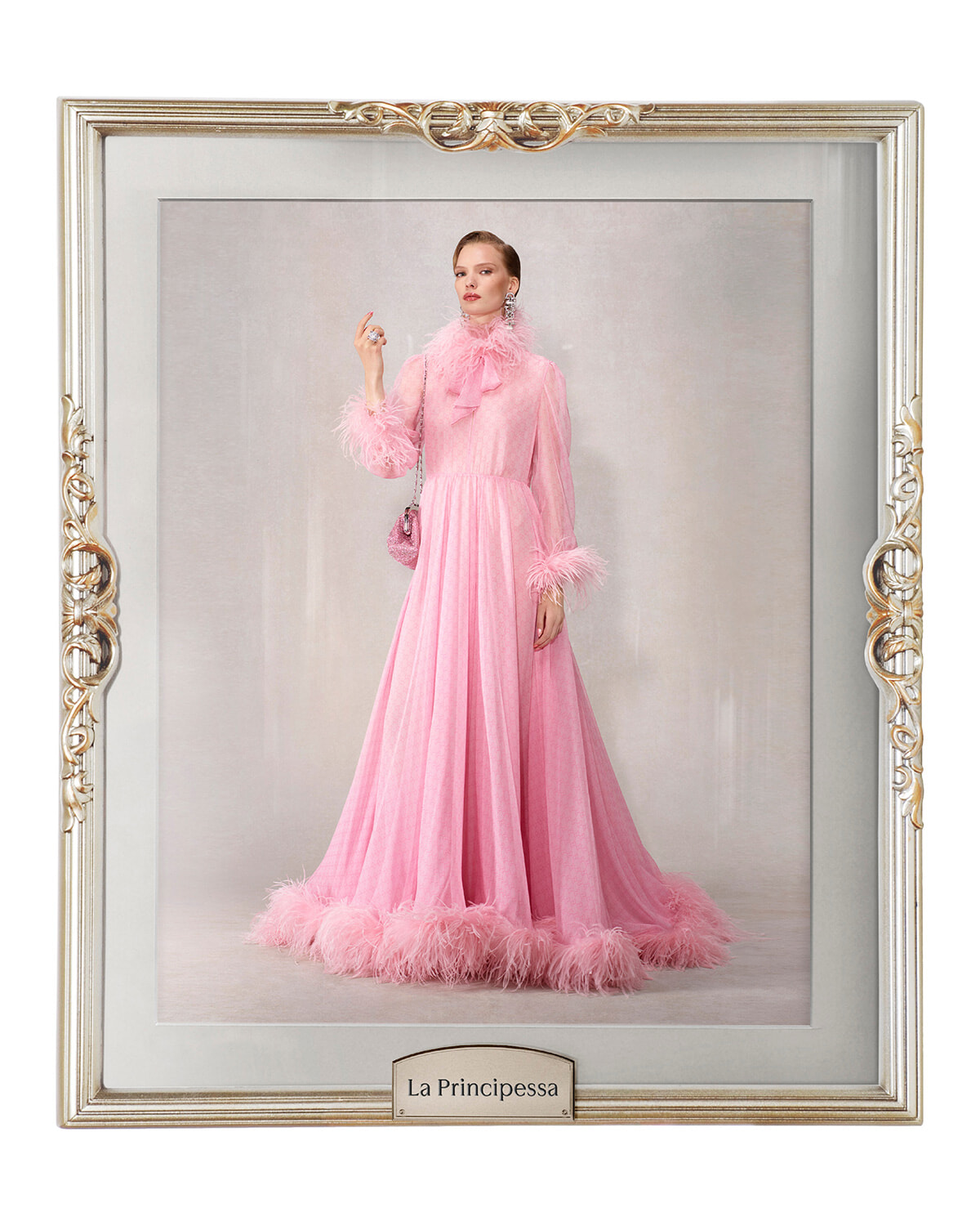 Portrait of a model in a floor-length pink feather-trimmed gown inside an ornate gold frame, La Principessa plaque below.