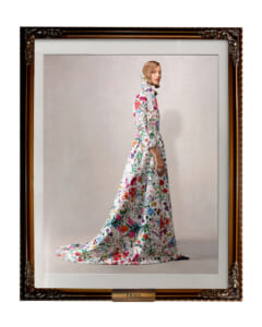 Model wearing a long white floral gown with a high collar, standing in profile inside an ornate frame labeled Flora.