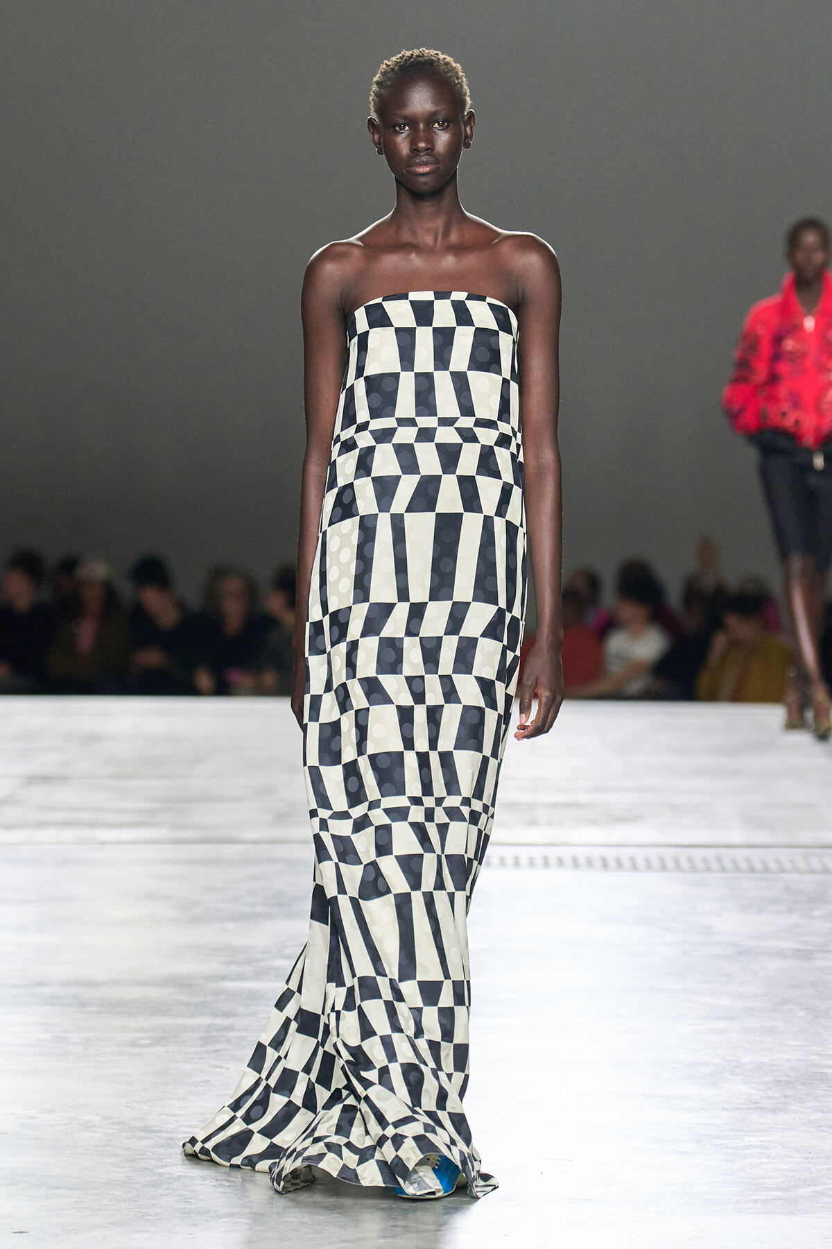Model walks the runway in a strapless, floor-length black-and-white geometric checkerboard dress on the catwalk.