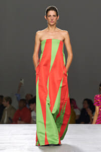 Strapless, floor-length dress with bold red and lime green geometric panels worn by a model on a runway.