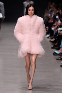Model walks the runway in a voluminous, pale pink fluffy coat with pink heels.