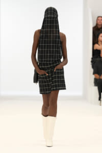 Runway model in a black-and-white grid-pattern two-piece set with a matching veil and white knee-high boots.
