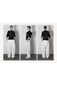 Triptych of a female model wearing a black draped top and wide white trousers, shown from front, side, and back in a studio setting.