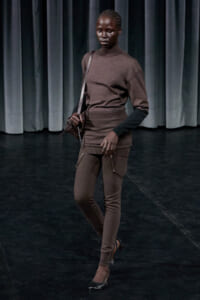 Model walking the runway in a brown knit matching top and pants with a brown crossbody bag.