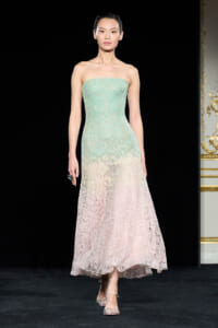 Strapless pastel lace gown on a model, gradient from mint green to pale pink, mid-runway pose.