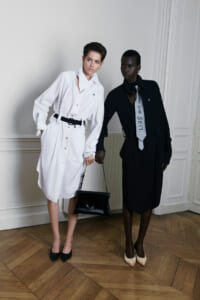 Two models pose indoors in monochrome outfits: white shirt-dress with black belt and black heels, and black shirt-dress with a light tie.